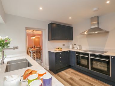 A kitchen with dark cabinets white countertops and stainless steel appliances at Hazelnut Cottage in Windermere
