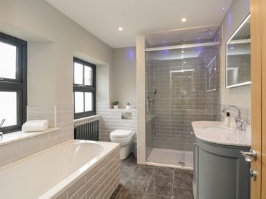 A bathroom with a bathtub, toilet, shower, and a sink at Hazelnut Cottage in Windermere