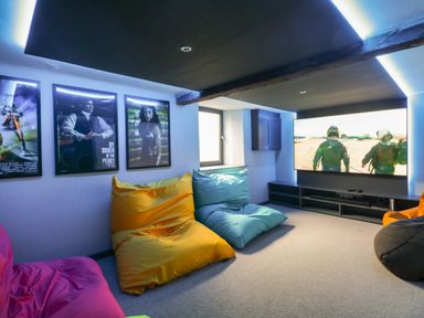 A media room with bean bags and a large screen television on the wall at Hazelnut Cottage in Windermere