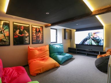 A media room with large screen tv colorful bean bags and framed movie posters on the wall at Hazelnut Cottage in Windermere