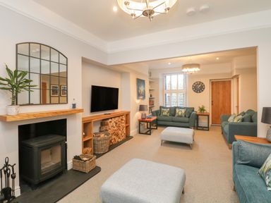 A living room with sofas a TV wood stove and a large mirror at Hazelnut Cottage in Windermere