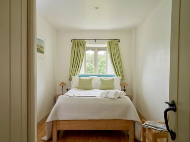 A bedroom with a bed cushions curtains and bedside lamps at Garden House in Cornworthy