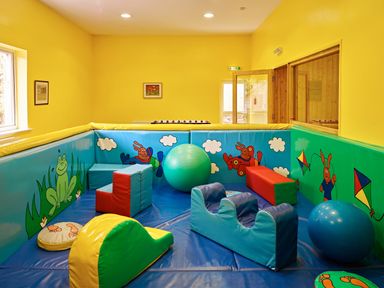 A children's playroom with soft padded toys and colorful wall murals at Garden House in Cornworthy