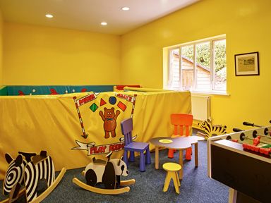 A playroom with rocking animals, small chairs, a table, and a foosball table at Garden House in Cornworthy