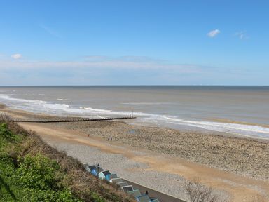 A beach with pebbles and sand next to the sea under a blue sky at Pebbles in Cromer