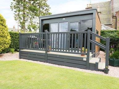 A small modern cabin with dark railing and a small deck in a garden at Cabin at the Tavern in Coupar Angus