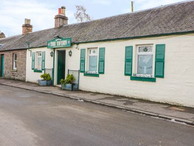 The exterior of a building with a sign that reads The Tavern and green shutters on the windows at Cabin at the Tavern in Coupar Angus