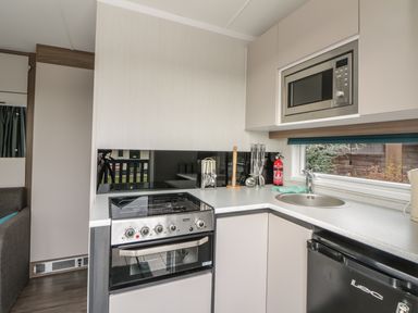 A kitchen with a stove oven microwave sink and refrigerator at Cabin at the Tavern in Coupar Angus