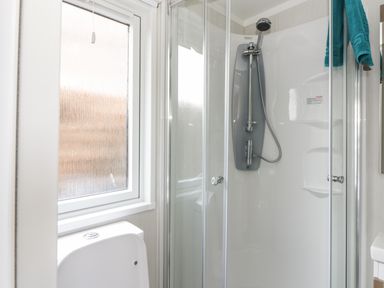 A bathroom with a shower cubicle a window and a toilet at Cabin at the Tavern in Coupar Angus