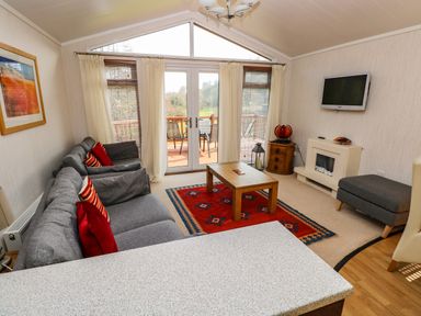 A living room with gray sofas and red pillows a wooden coffee table and a red patterned rug at Jules @ 79 in Stepaside