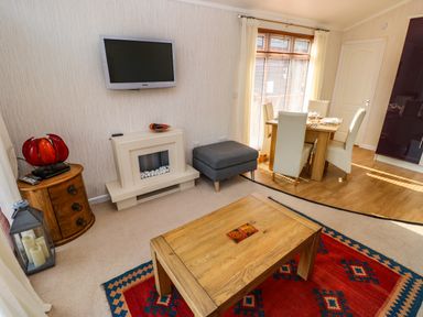 A living room with a wooden coffee table and a red patterned rug near a dining area with a wooden table and white chairs at Jules @ 79 in Stepaside