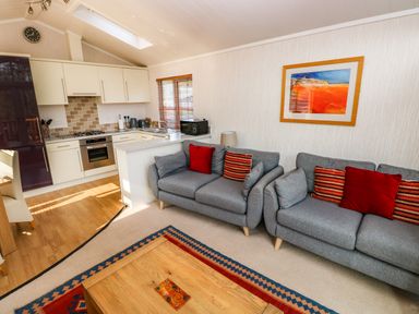A living room with two gray sofas with red and striped cushions near a wooden coffee table and an open kitchen at Jules @ 79 in Stepaside