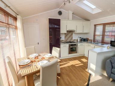 A kitchen and dining area with a wooden table set for four and white cabinets at Jules @ 79 in Stepaside