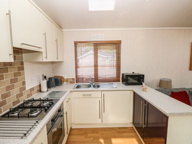 A kitchen with a gas stove oven microwave sink and blinds on the window at Jules 79 in Stepaside