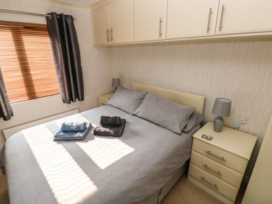 A bedroom with a bed gray bedding towels on the bed bedside tables with lamps and cabinets above Jules @ 79 in Stepaside