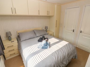 A bedroom with a double bed gray bedding and towels on the bed along with built in cabinets bedside tables and lamps at Jules @ 79 in Stepaside