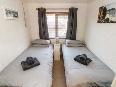 A bedroom with two single beds with grey bedding and dark towels placed on each bed at Jules @ 79 in Stepaside