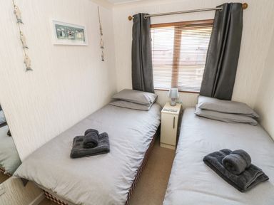 A bedroom with two single beds separated by a nightstand with a lamp and window blinds at Jules @ 79 in Stepaside