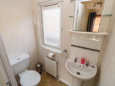 A bathroom with a toilet sink mirror window radiator and trash bin at Jules 79 in Stepaside