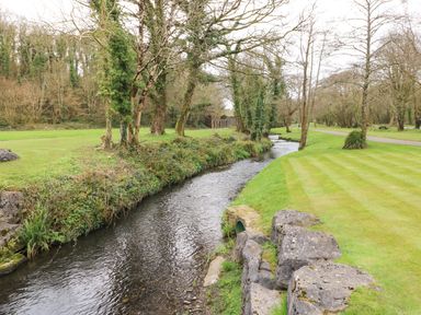 A narrow river flowing through a park with grass and trees at Jules @ 79 in Stepaside