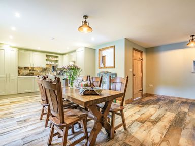 A kitchen dining area with a wooden table and chairs and light green cabinets at Meadowsweet Goathland