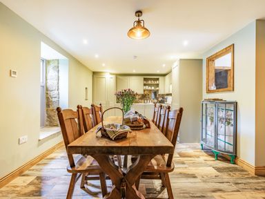 A dining room with a wooden table and chairs and a kitchen area at Meadowsweet in Goathland