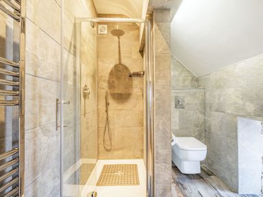 A bathroom with a glass shower enclosure and wall-mounted toilet at Meadowsweet in Goathland