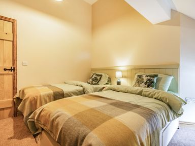 A bedroom with two single beds with checkered blankets and a bedside lamp at Meadowsweet in Goathland