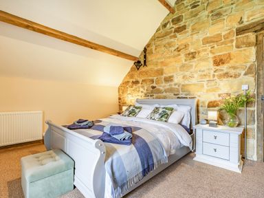 A bedroom with a double bed bedside table and ottoman at Meadowsweet in Goathland