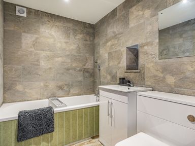 A bathroom with a bathtub with a dark towel on the side a white sink cabinet and a toilet at Meadowsweet in Goathland