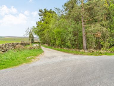 A rural road intersection with stone walls and trees alongside the roads at Meadowsweet in Goathland