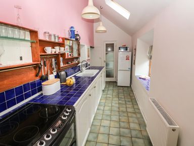 A kitchen with a tiled counter and backsplash dish rack sink stove refrigerator and a window at Pant y FFynnon in St Davids