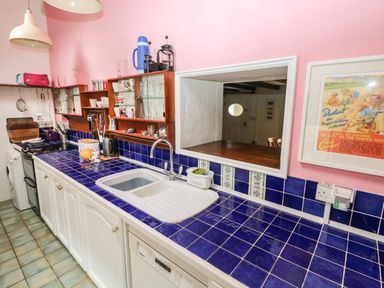 A kitchen with blue tiled countertop white cabinets and pink walls at Pant y FFynnon in St Davids
