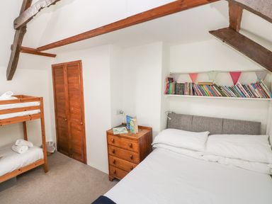 A bedroom with a double bed a bunk bed a wooden chest of drawers and a bookshelf with books at Pant y FFynnon in St Davids