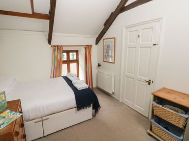 A bedroom with a bed with towels on it a wooden dresser and a cabinet with wicker baskets at Pant y FFynnon in St Davids