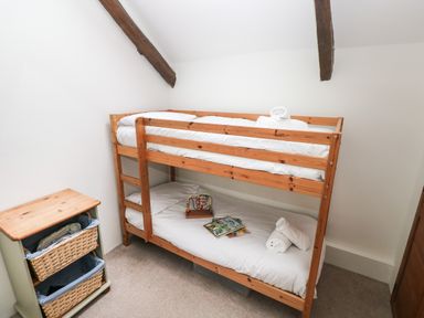 A small bedroom with wooden bunk beds and a side table with wicker baskets at Pant y FFynnon in St Davids