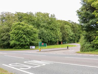 A road intersection with a sign for Kenwick Park Estate surrounded by trees at Great Leap in Louth