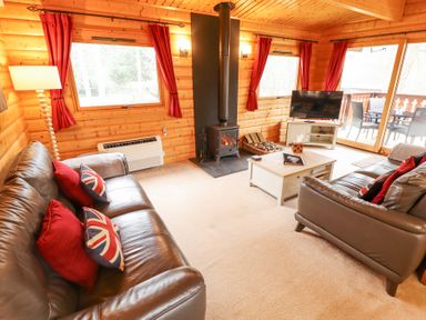 A living room with leather sofas and red curtains around windows at Great Leap in Louth