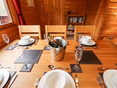 A dining table set with bowls plates cutlery glasses and a champagne bottle in an ice bucket in a wooden room at Great Leap in Louth