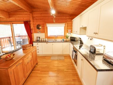 A kitchen with white cabinets black countertops wooden island and dining area outside at Great Leap in Louth
