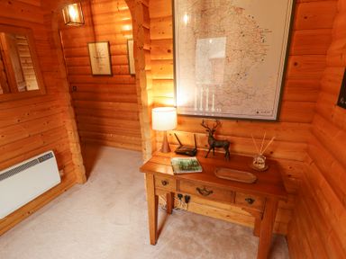 A wooden room with a table holding a lamp, router, deer figurine, book, and reed diffuser at Great Leap in Louth