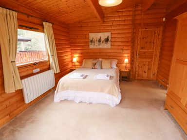 A bedroom with a double bed lamps on bedside tables a window with curtains and wooden furniture at Great Leap in Louth