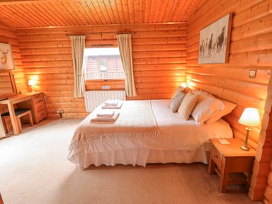 A bedroom with a double bed pillows towels bedside tables lamps a desk and a window with curtains at Great Leap in Louth
