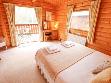 A bedroom with a bed and towels on it a wooden desk with a mirror and lamp a sliding door leading to a balcony with a table and two chairs at Great Leap in Louth