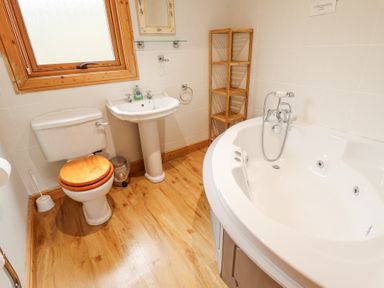 A bathroom with a toilet sink wooden shelving unit and a bathtub at Great Leap in Louth