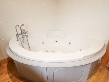 A corner bathtub with silver faucet and white tiled walls at Great Leap in Louth
