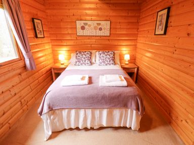 A bedroom with a double bed bedside tables lamps framed pictures and a window at Great Leap in Louth