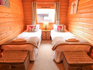 A bedroom with two single beds a window in between and wooden walls at Great Leap in Louth