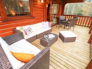 An outdoor wooden deck with wicker seating furniture cushions and a round dining table at Great Leap in Louth