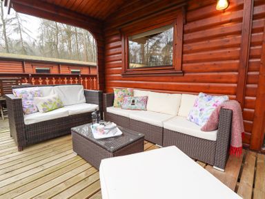 An outdoor seating area with wicker sofas cushions and a coffee table on a wooden deck at Great Leap in Louth